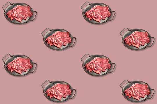 Repeating pattern of raw beef bacon slices fanned inside black handled pans against a soft muted pink background