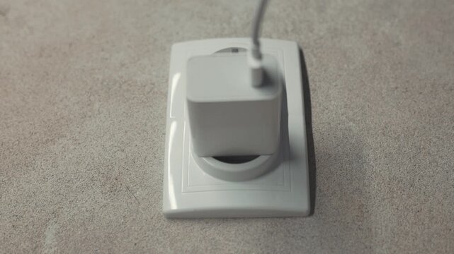Hand Plugging Charger Cable Into Wall Socket And Unplugging It, Close Up Concept Of Saving Energy And Electricity