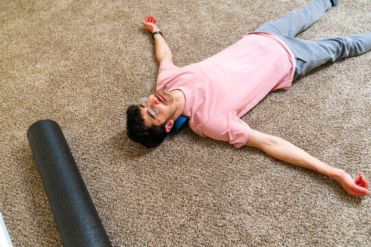 man doing exercise at home stretching neck foam roller