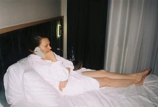 Woman on Phone Sitting on Bed in Hotel Room
