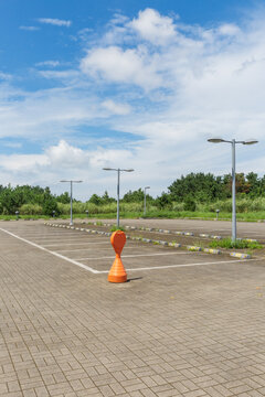 Orange Traffic Cone in Empty Outdoor Parking Lot Under Blue Sky