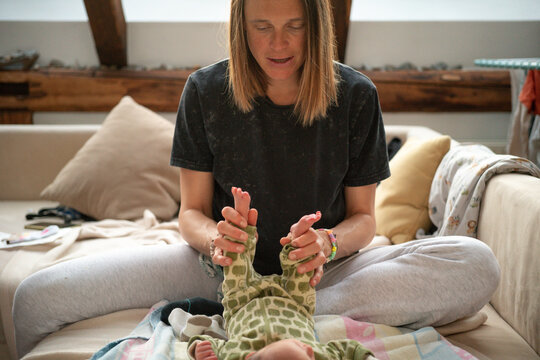 Mother playing with the feet of her newborn daughter