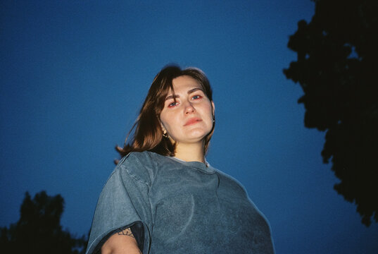 Young woman portrait looking up against blue evening sky