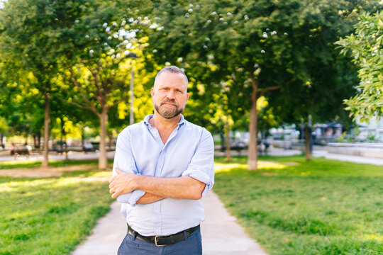 Middle-aged man with beard posing confidently in park