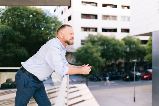 Mature man contemplating city life from balcony