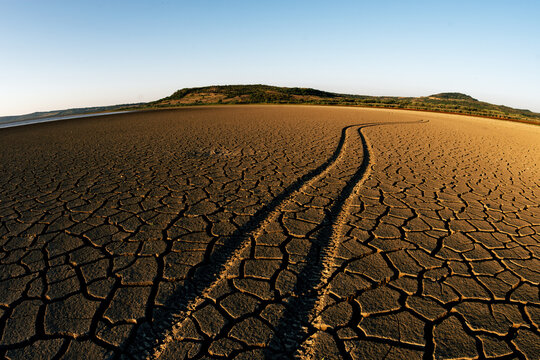 Tracks on dry land at drought affected area with sunset light
