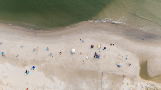 People Enjoying a Beach Day With Umbrellas and Equipment