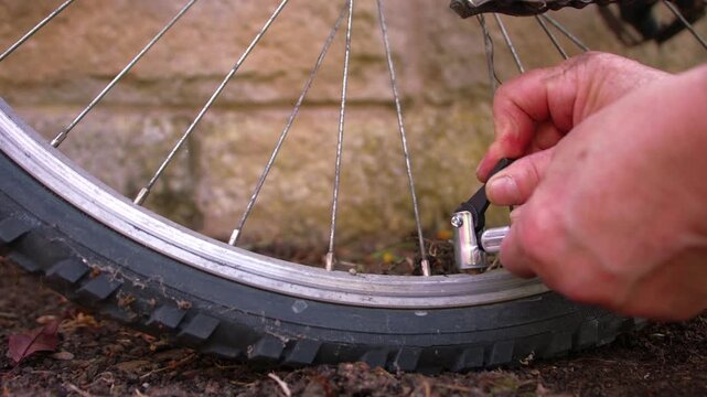 Cyclist pumping flat tyre on bicycle