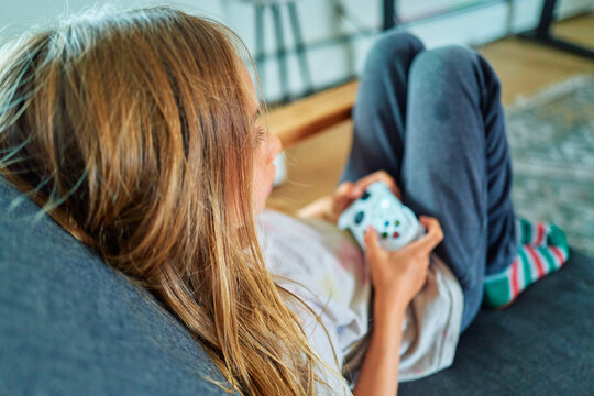 Boy Holding a Game Controller on a Grey Sofa From Above