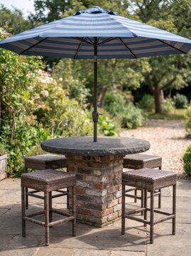 Outdoor garden bar set featuring stone table top on brick base with striped patio umbrella.
