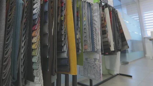 Furniture and upholstery fabric samples hang on a display stand in the showroom of a furniture factory or store. The display of furniture fabric samples arranged on an exhibition stand in showroom. 
