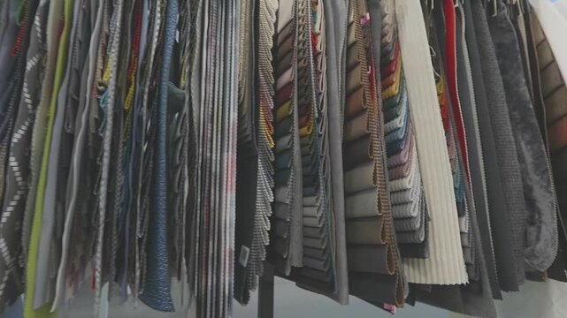 The display of furniture fabric samples arranged on an exhibition stand in an office or furniture factory showroom. Furniture and upholstery fabric samples hang on a display stand. Close-up