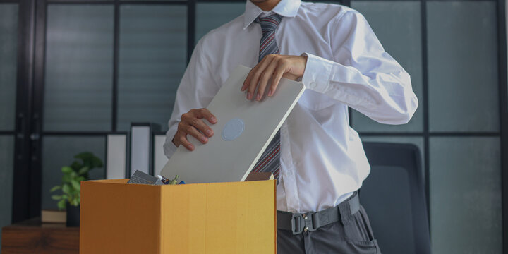 Male employee packing office desk items into box after job termination or resignation.
