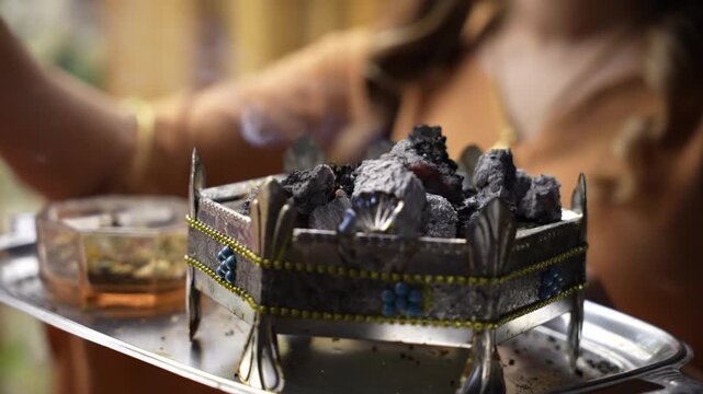 Traditional Middle Eastern ceremony showcasing wild rue seeds burning on a decorative metal charcoal brazier producing aromatic smoke to ward off the evil eye during cultural wedding events.