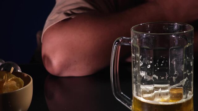Depressed  man sitting at a kitchen counter with a beer mug, struggling with alcohol addiction and mental health issues