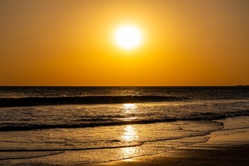 Golden sun setting over the Atlantic Ocean with glittering waves on a sandy beach © Ronny Gängler