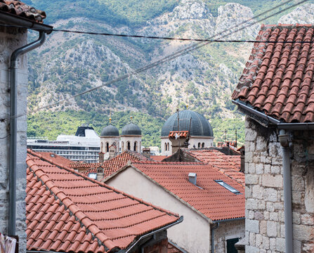 Red terracotta tiled rooftops in the Old Town of Kotor lead towards the domes of St Nicholas Church