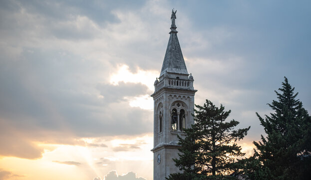 Historic stone bell tower rises against a dramatic cloudy sunset sky in Montenegro