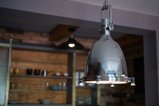 Polished chrome pendant lamp hangs illuminated in a modern interior