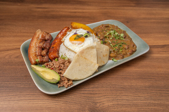 Hearty Latin American combination meal featuring savory sausage, ground meat, and avocado on a ceramic dish.