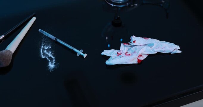 Dark tabletop with syringe, white powder, makeup brush, and blood-stained tissues beside a glass, suggesting drug use and crime scene evidence.