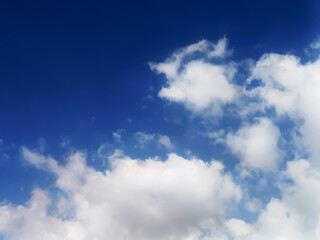 White cumulus clouds drift across a vibrant blue sky during a bright sunny day with soft daylight © Md