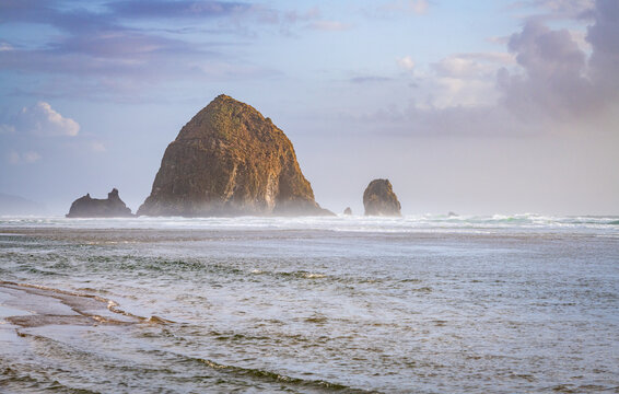 Haystack Rock rises along the misty Pacific Ocean shoreline at Cannon Beach on the northern Oregon Coast.