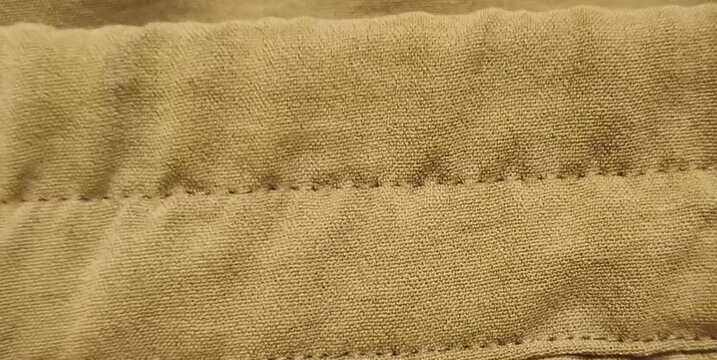 Close up of tan elastic waistband stitching detail on fabric texture