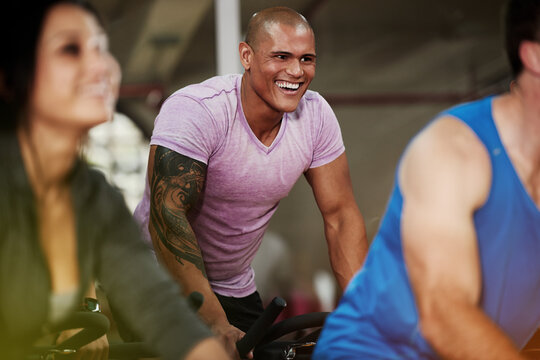 Smile, spin class or man on cycling equipment in training exercise for wellness, health or fitness. Active, challenge or happy athlete on bicycle machine for workout, body or cardio in gym community