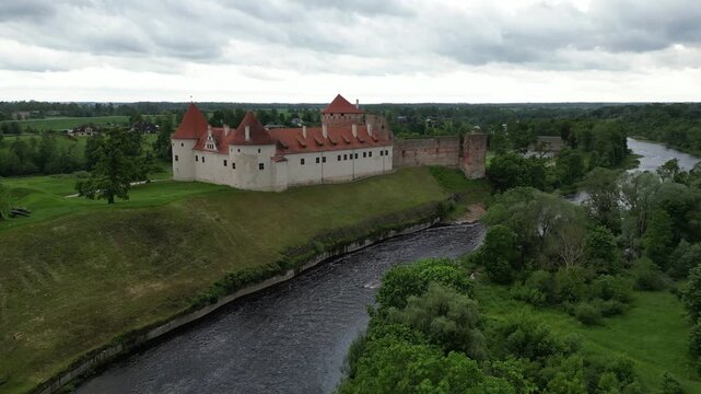 Aerial view of a Bauska castle surrounded by trees and a river