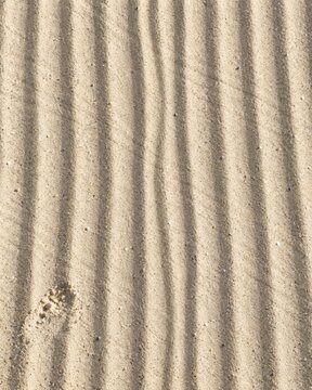 Pale beige sand with raked parallel ripples, featuring a dry granular texture and soft side lighting for a calming background and copy space