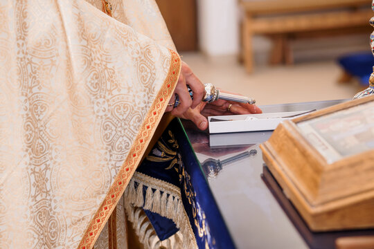 Priest in Ornate Vestments Blesses Holy Water at Church Altar with Silver Aspergillum