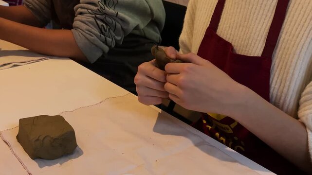 Young woman kneading clay by hand, pottery master class