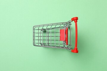 Small silver shopping cart on green background, top view © Sunlight