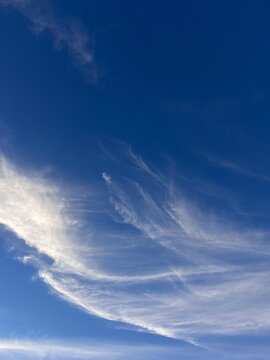 Beautiful diagonal cirrus clouds in the blue sky, abstract natural background with windy cloudscape and copy space.
