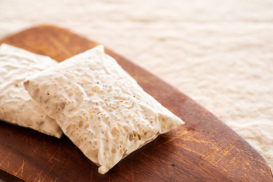Fresh raw soybean tempeh blocks on a wooden cutting board.