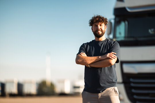 Truck driver posing confidently in front of a large transport vehicle
