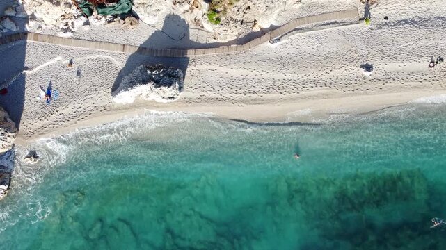 Person swimming in turquoise ocean water near a white sand beach in a tropical destination, aerial drone view of a p. Stunning overhead shot of a crystal clear tropical beach with white sand and turqu