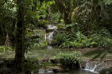 Scenic waterfall cascade hidden in lush tropical jungle with calm natural pool at Erawan National Park Kanchanaburi Thailand © VaZu Photo