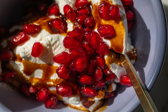 pomegranate arils on greek yogurt with pomegranate molasses in purple bowl 