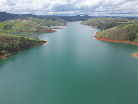 Visto de cima com drone represa cheia e bonita com paisagens ao fundo de montanhas.