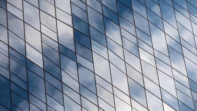 Modern Glass Skyscraper Facade Reflecting Blue Sky and Clouds