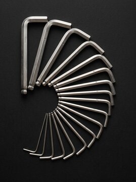 Set of metal hex keys arranged in a fan pattern on a dark background