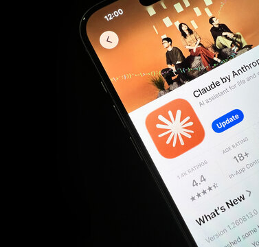 Close up of smartphone screen showing Claude AI assistant app update, illustrative editorial backdrop