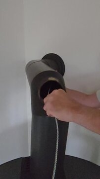 Man pulls a flexible wire brush out of a stovepipe inspection hatch in a vertical closeup.