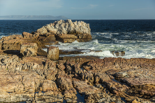 large pounding waves and spray hitting rocky cliffs of Hermanus South African coastline