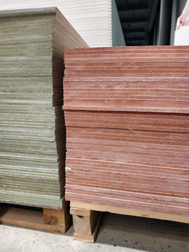 Magnesite wall sheet panels stacked on pallets in construction supermarket with hardware products and repair material display