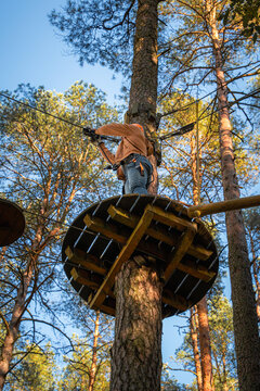 Person Climbing High Ropes Course on Wooden Platform in Forest