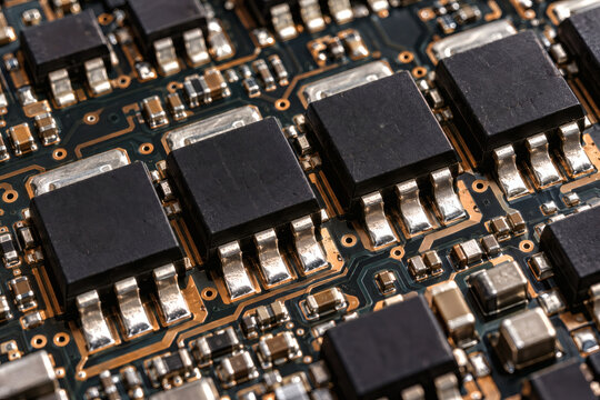 Extreme macro photograph of modern semiconductor transistors on a multilayer PCB, black electronic packages with precise symmetry, silver solder joints, copper traces, realistic manufacturing detail