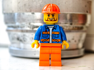 Naklejka premium Russia, St. Petersburg, August 8, 2020 A close-up of a Lego minifigure wearing a hard hat, suitable for use in illustrations related to building or construction